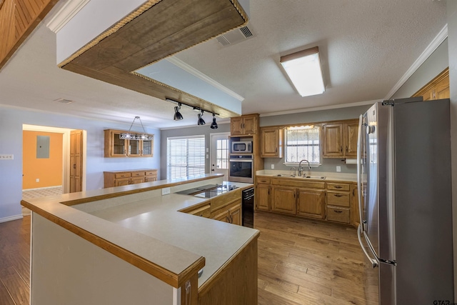 kitchen with appliances with stainless steel finishes, a center island, crown molding, and sink