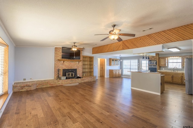 unfurnished living room with sink, plenty of natural light, a textured ceiling, and a wood stove