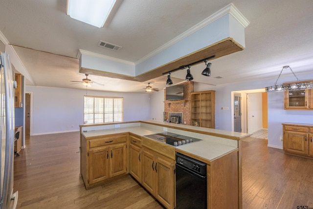 kitchen with track lighting, kitchen peninsula, ornamental molding, black electric cooktop, and a brick fireplace