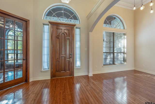 entrance foyer featuring crown molding, wood-type flooring, and a high ceiling