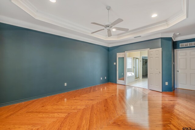 empty room with ceiling fan, light parquet floors, crown molding, and a tray ceiling