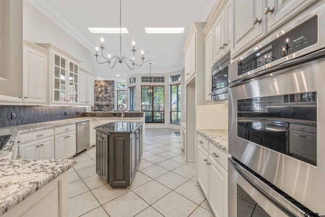 kitchen featuring pendant lighting, an inviting chandelier, decorative backsplash, ornamental molding, and appliances with stainless steel finishes