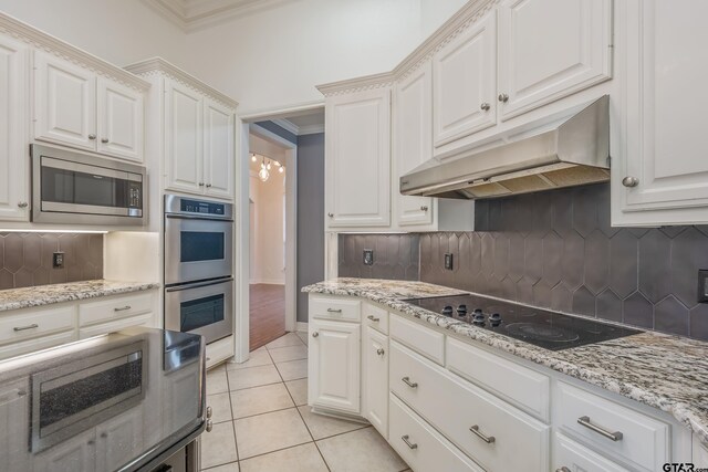 kitchen with backsplash, white cabinets, light tile patterned floors, ornamental molding, and stainless steel appliances