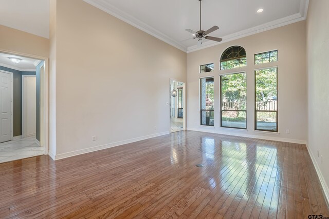 unfurnished room with a towering ceiling, light hardwood / wood-style floors, and ornamental molding