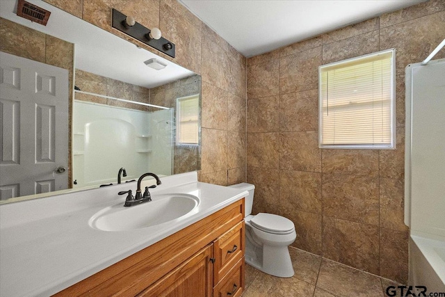 full bath featuring walk in shower, vanity, visible vents, toilet, and tile walls