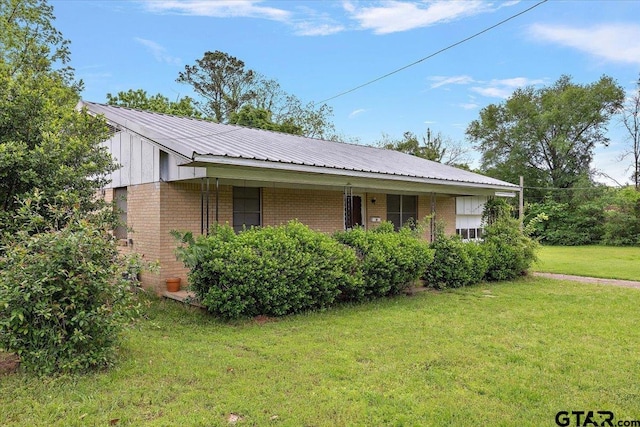 view of side of home with brick siding, a lawn, and metal roof