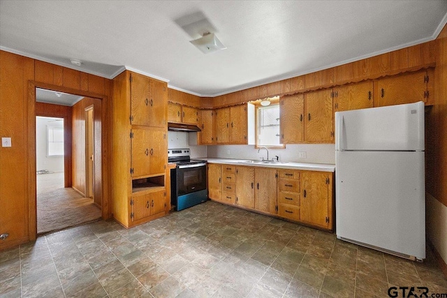 kitchen featuring range with electric stovetop, a sink, freestanding refrigerator, under cabinet range hood, and wooden walls