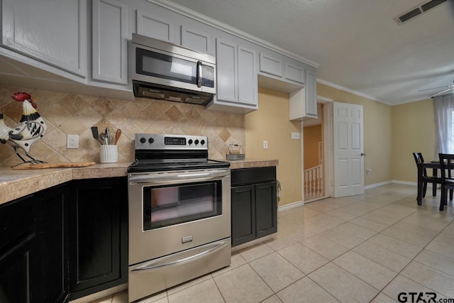 kitchen with appliances with stainless steel finishes, tasteful backsplash, ornamental molding, ceiling fan, and light tile patterned floors