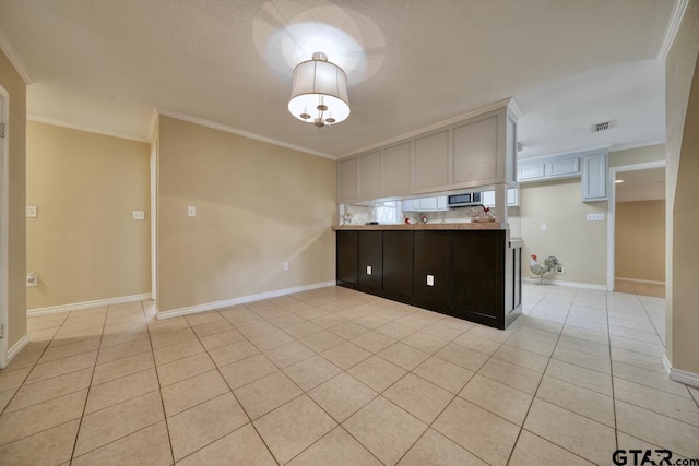 kitchen with dark brown cabinets, crown molding, and light tile patterned flooring