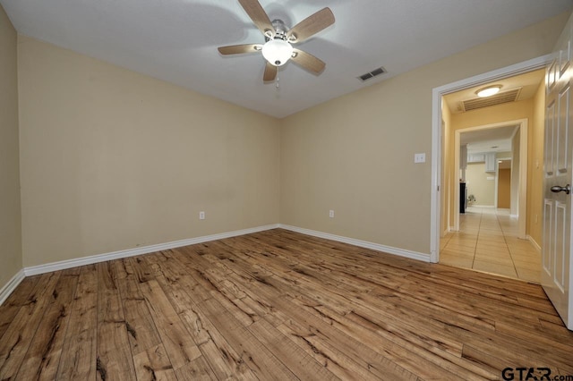 empty room with ceiling fan and light hardwood / wood-style flooring