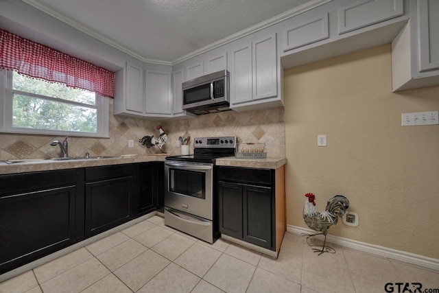 kitchen featuring sink, stainless steel appliances, crown molding, decorative backsplash, and light tile patterned flooring