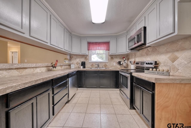 kitchen featuring gray cabinetry, sink, stainless steel appliances, backsplash, and light tile patterned floors