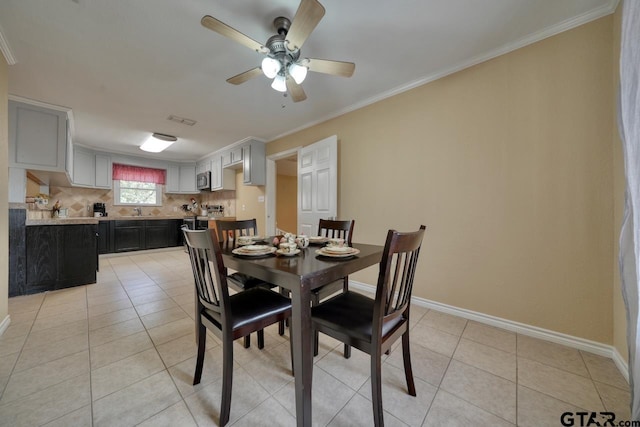 tiled dining space with ceiling fan, sink, and ornamental molding