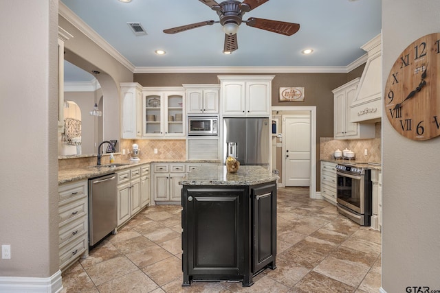 kitchen with a kitchen island, sink, light stone counters, stainless steel appliances, and custom range hood