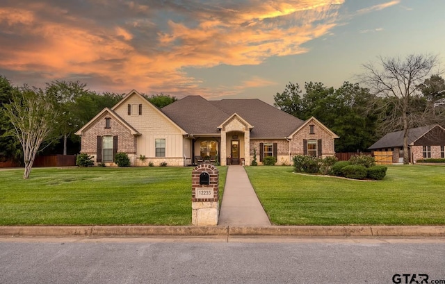 view of front of house featuring brick siding, a yard, and fence