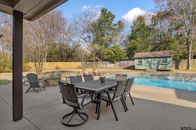 view of patio / terrace featuring an outdoor fire pit, a fenced in pool, and a shed