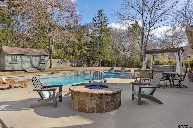 view of swimming pool with a patio, a jacuzzi, an outdoor fire pit, a pergola, and a storage shed