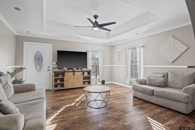 living room featuring ceiling fan, dark hardwood / wood-style flooring, ornamental molding, and a tray ceiling