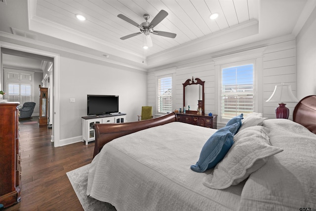 bedroom featuring multiple windows, dark wood-type flooring, and a tray ceiling