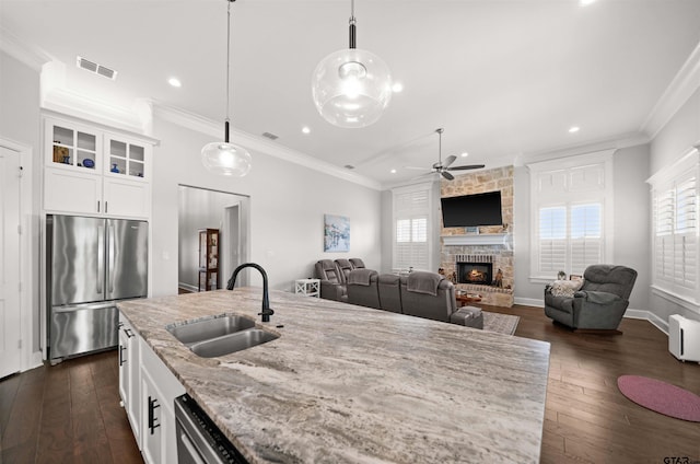 kitchen featuring pendant lighting, white cabinetry, sink, stainless steel fridge, and light stone counters