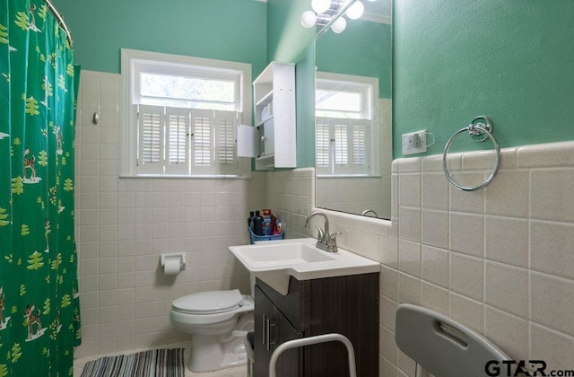 1017 Hilltop Dr, Palestine, TX 75801 - bathroom with tile walls, a wainscoted wall, vanity, toilet, and a shower with shower curtain
