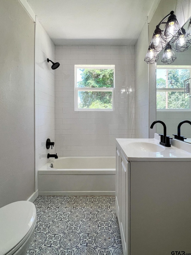 full bathroom with toilet, vanity, a wealth of natural light, and tiled shower / bath