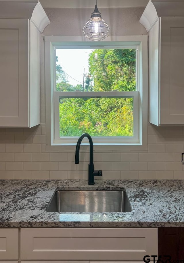 interior details with white cabinetry, sink, and decorative backsplash