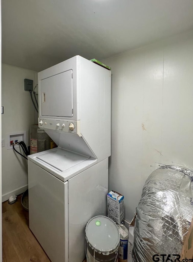 laundry room with hardwood / wood-style floors and stacked washing maching and dryer