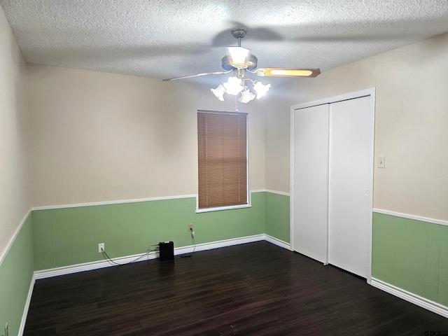 unfurnished bedroom with a textured ceiling, ceiling fan, dark wood-type flooring, and a closet