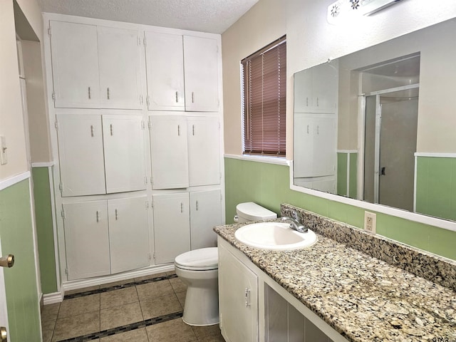 bathroom with vanity, tile patterned flooring, toilet, a textured ceiling, and a shower with shower door