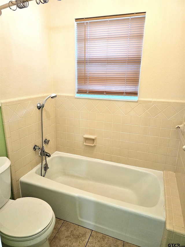 bathroom featuring toilet, tile patterned floors, tile walls, and a washtub