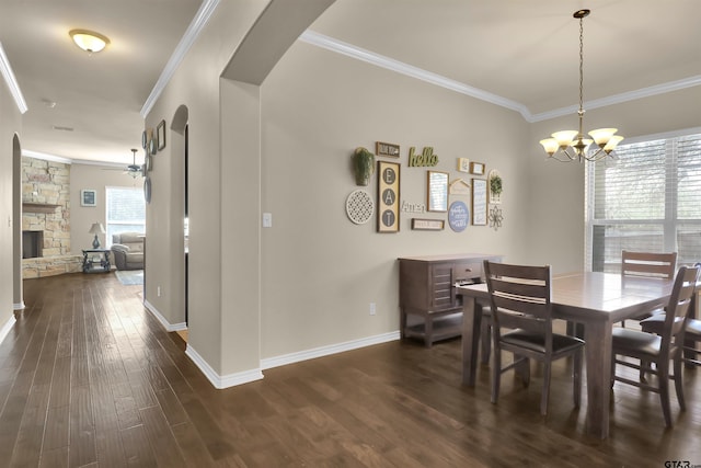 dining area with dark hardwood / wood-style flooring, a fireplace, ceiling fan with notable chandelier, and ornamental molding