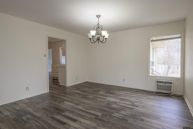 empty room with dark wood-type flooring, a wall mounted air conditioner, and an inviting chandelier