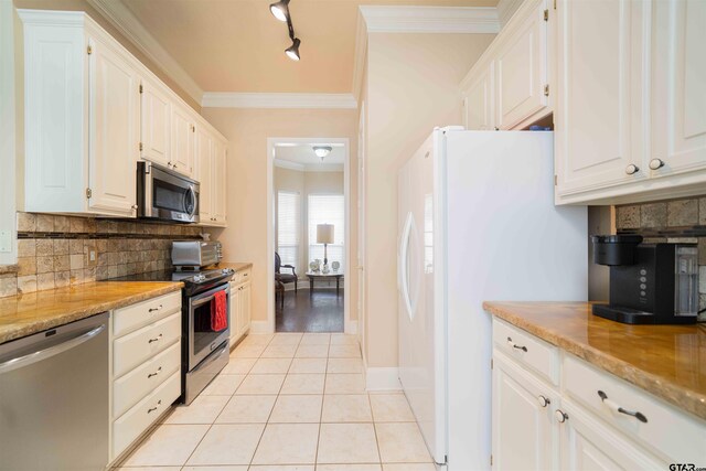 2215 Homestead Ln, Tyler, TX 75701 - kitchen featuring ornamental molding, light tile patterned flooring, white cabinetry, decorative backsplash, and appliances with stainless steel finishes