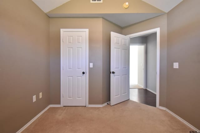 unfurnished bedroom with light colored carpet and vaulted ceiling