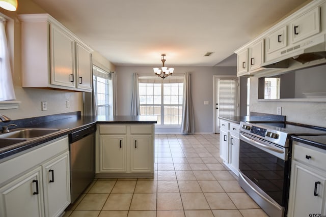 kitchen with light tile patterned flooring, appliances with stainless steel finishes, kitchen peninsula, a notable chandelier, and white cabinets