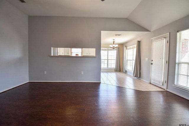 unfurnished room featuring an inviting chandelier, vaulted ceiling, light hardwood / wood-style floors, and a healthy amount of sunlight