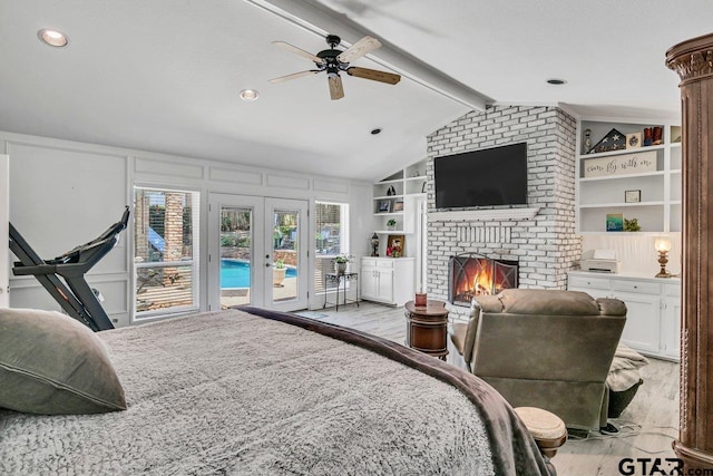 bedroom featuring vaulted ceiling with beams, ceiling fan, access to exterior, a fireplace, and light hardwood / wood-style floors