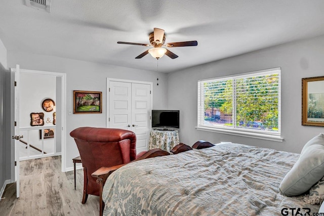 bedroom with ceiling fan, light hardwood / wood-style floors, and a closet