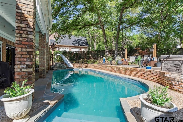 view of pool with exterior kitchen, a patio, and a water slide