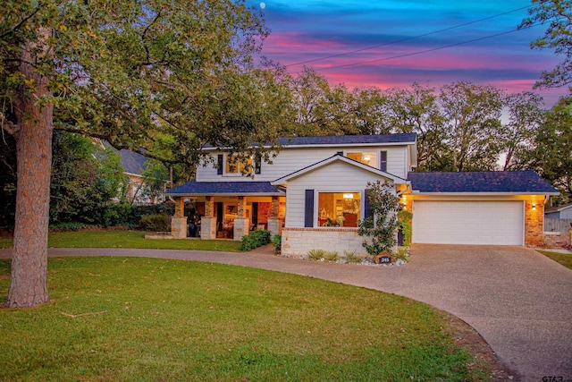 front facade featuring covered porch, a yard, and a garage