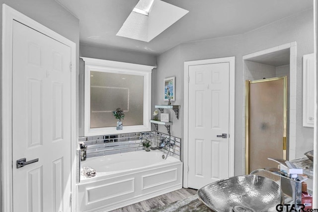 bathroom with shower with separate bathtub, a skylight, and wood-type flooring