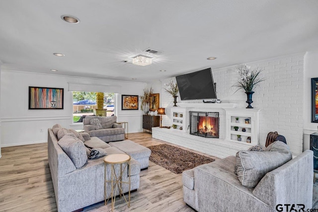 living room with a fireplace, light hardwood / wood-style flooring, and brick wall