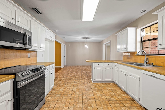 kitchen featuring appliances with stainless steel finishes, white cabinets, pendant lighting, sink, and kitchen peninsula