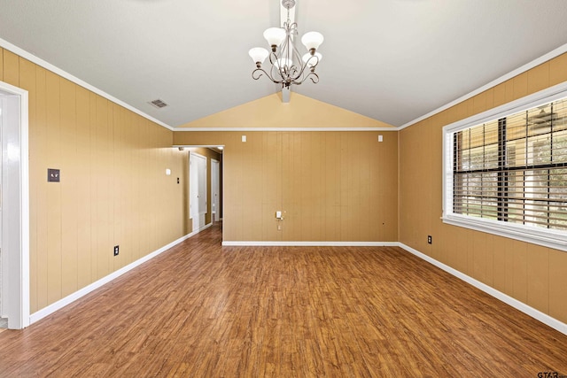 spare room with hardwood / wood-style flooring, a chandelier, crown molding, and vaulted ceiling