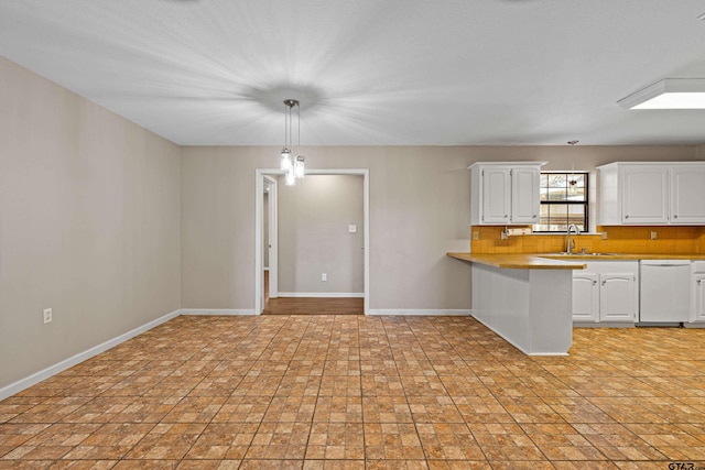 kitchen with white cabinetry, kitchen peninsula, dishwasher, and decorative light fixtures