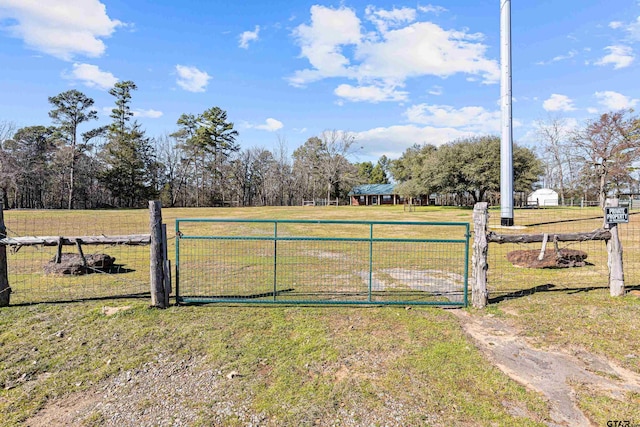 view of gate with a rural view and a lawn