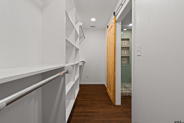 spacious closet with dark hardwood / wood-style floors and a barn door