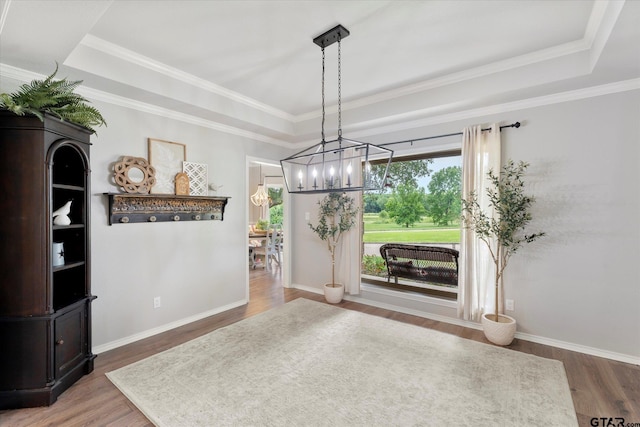 dining space featuring hardwood / wood-style flooring, a tray ceiling, ornamental molding, and a chandelier