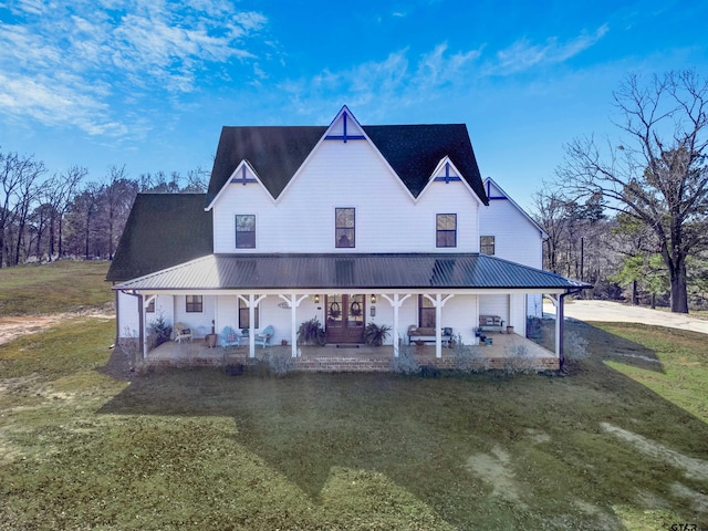 back of property with metal roof, a patio area, and a lawn